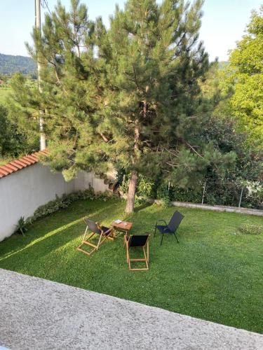 2 chaises et une table dans une cour avec un arbre dans l'établissement Vila Bilja, à Požega
