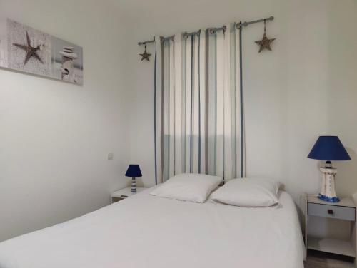 - une chambre avec un lit blanc et deux lampes dans l'établissement L'Albatros- Parking - Piscine, à La Rochelle