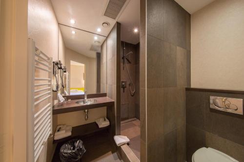 a bathroom with a shower and a toilet and a sink at Hotel Des Lices in Rennes