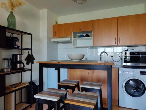 une cuisine avec des armoires en bois et un comptoir avec des tabourets dans l'établissement L'Escapade 1 chambre-parking-piscine, à La Rochelle