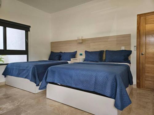 a bedroom with two beds with blue sheets and a window at Relax Beach Front Residence in Las Terrenas