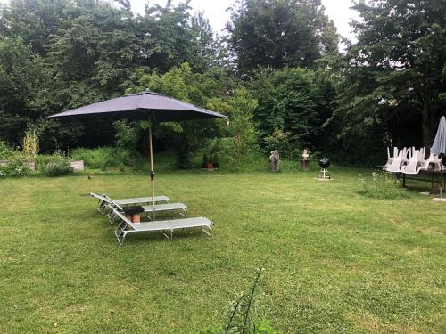 a group of lounge chairs and an umbrella in a yard at Secret Garden Villa in Pörtschach am Wörthersee