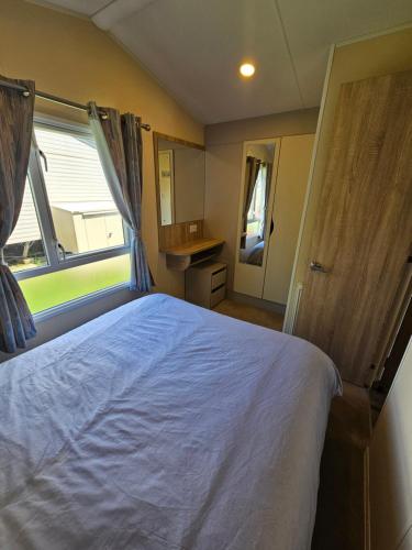a bedroom with a bed and a large window at Cosy Caravan Haven Marton Mere in Blackpool