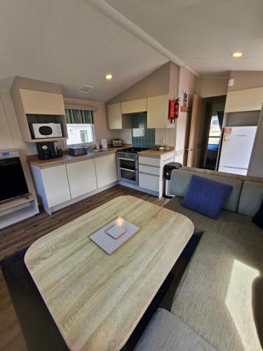 a living room with a table and a kitchen at Cosy Caravan Haven Marton Mere in Blackpool