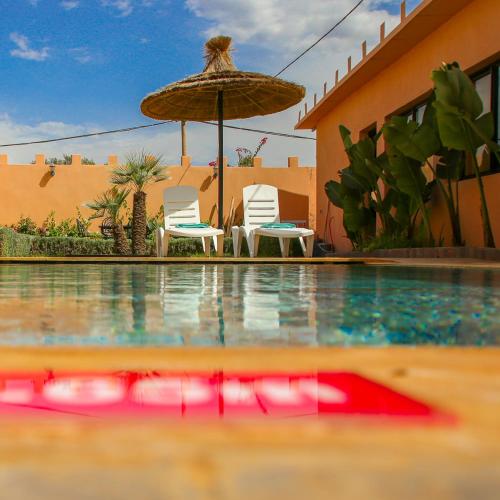 two chairs and an umbrella next to a swimming pool at Villa Kasbah in Marrakech