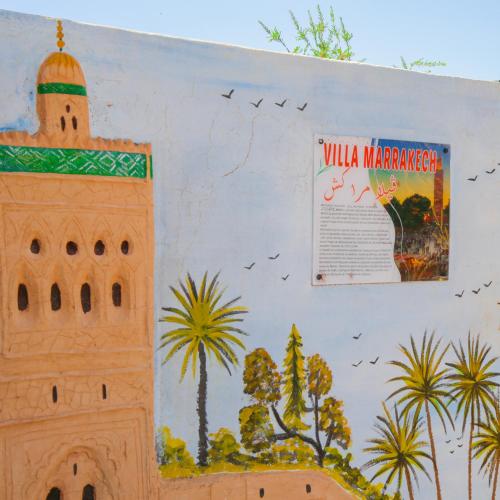 a wall with a mural of a building and a poster at Villa Kasbah in Marrakech