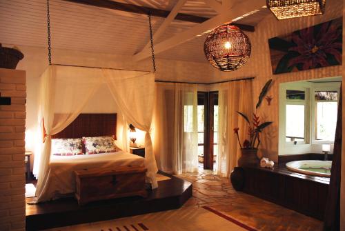 een slaapkamer met een bed en een bad in een kamer bij Pousada e SPA Bromelias in Paraty
