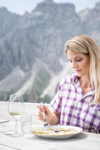a woman sitting at a table with a plate of food at Hotel Elisabeth in Chienes