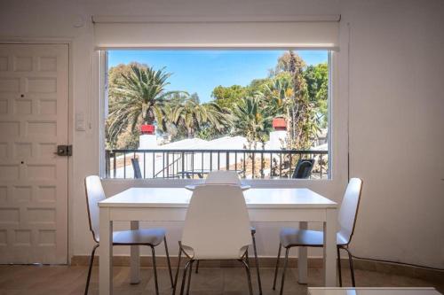 Una mesa y sillas blancas en una habitación con ventana. en Altafulla, primera linea de mar con acceso directo a la playa, en Altafulla
