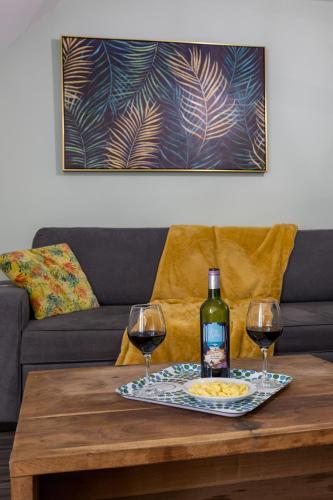 - une bouteille de vin et deux verres sur une table basse dans l'établissement Le Jungle - hyper centre, à Mont-de-Marsan