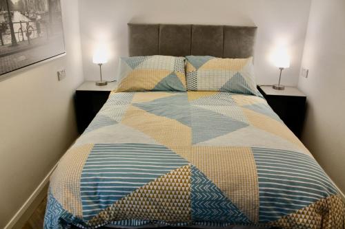 a bed with a colorful quilt on it with two lamps at Contemporary Countryside Home in Dromore