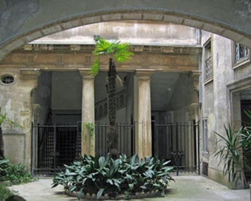 un bâtiment avec un palmier dans une cour dans l'établissement Ecusson - Duplex lumineux et climatisé dans hôtel particulier, à Montpellier