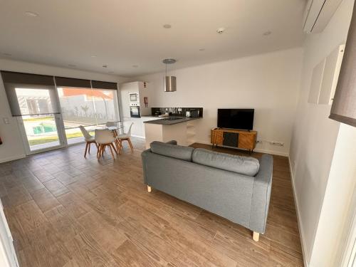 a living room with a gray couch and a kitchen at D'Felicidade in Caldas da Rainha