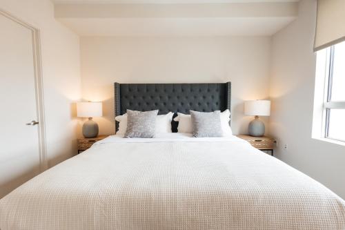 a white bedroom with a large bed with two lamps at Lovely 1 BD in West Hollywood in Los Angeles