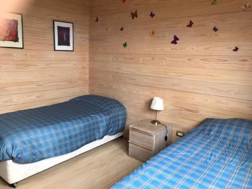 a bedroom with two beds and wooden walls at CÓMODA CASA FAMILIAR Punta Lobos in Pichilemu