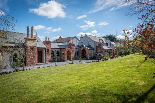 a large brick house with a green lawn at Heathfield Hall, Hillsborough - The Reflectory in Annahilt