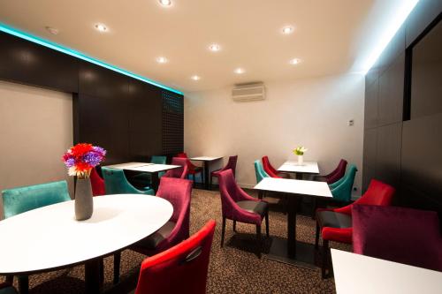 a dining room with tables and chairs and red chairs at Hotel Des Lices in Rennes