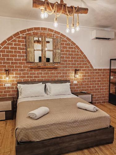 a bedroom with a large bed with a brick wall at S'Arrioleddu in Muravera