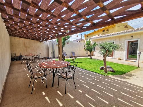 a patio with tables and chairs under a wooden pergola at S'Arrioleddu in Muravera