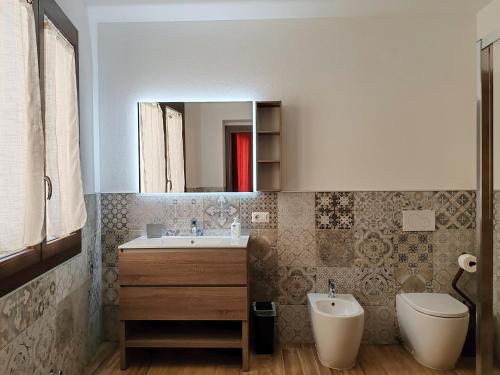 a bathroom with a sink and a toilet and a mirror at S'Arrioleddu in Muravera