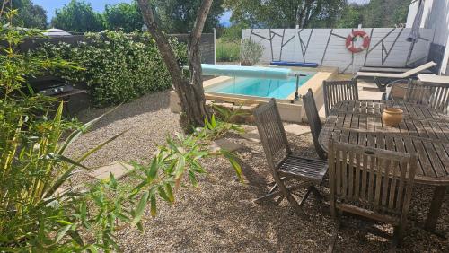 un patio avec une table et des chaises à côté d'une piscine dans l'établissement Bergerie saint-claude, à Bessan