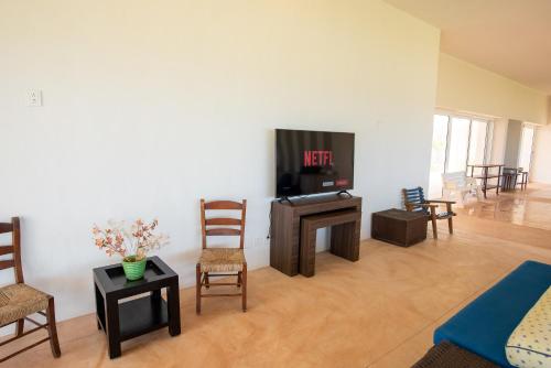 a living room with a flat screen tv and chairs at 97985 Stunning beachfront Suites Wi-Fi East of Progreso in Chicxulub