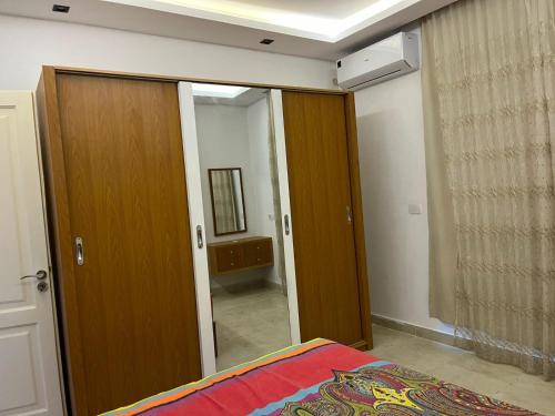 a bedroom with a wooden door and a mirror at Stylish 2-Bedroom Apartment in Celia Compound, New Administrative Capital in Madīnat al Amal