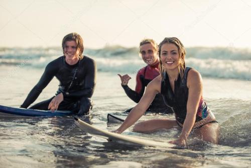 three surfers sitting on their surfboards on the beach at Cozy Beach Camp in Agadir