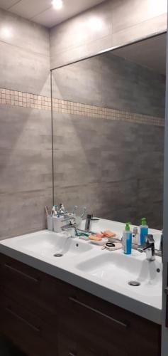 une salle de bain avec un lavabo blanc et un miroir dans l'établissement Grand appartement lumineux vue mer, à La Rochelle