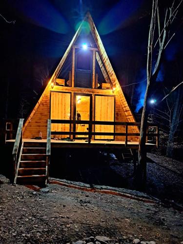 a cabin with a thatched roof at night at CabanaAframe in Curtea de Argeş