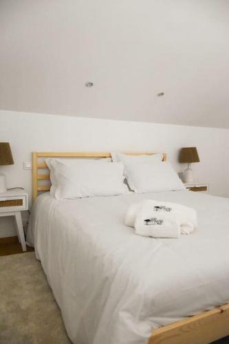 a large white bed with white sheets and pillows at Casa do Pátio do Tejo Nº8 in Sarilhos Pequenos