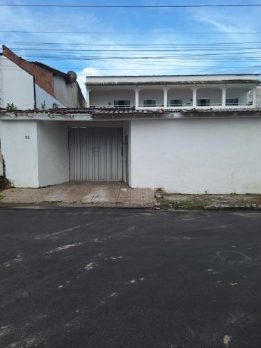 a white building with a gate and a garage at Quarto triplo com banheiro em Pousada e Restaurante in Manaus