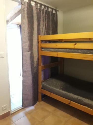 Ce lit superposé se trouve dans un dortoir doté d'une fenêtre. dans l'établissement Appartement T2 entre mer et montagne proche Calvi, à Calenzana