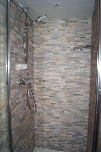 La salle de bains est pourvue d'une douche et d'un mur en briques. dans l'établissement SPA & Tiny house à la campagne, à La Boissière
