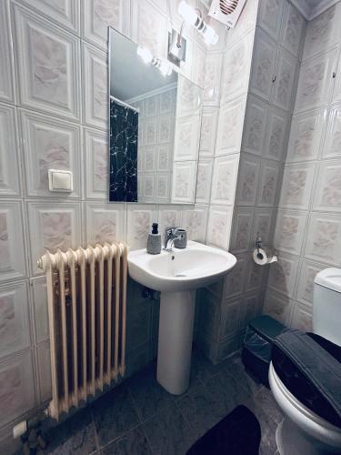 a bathroom with a sink and a mirror and a radiator at Aurora Apartments in Mytilini