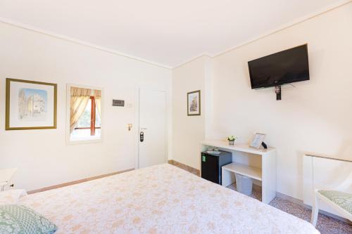 a white room with a bed and a tv on the wall at Villa Capitorsola in Capoliveri