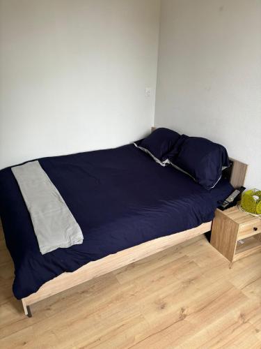 un lit avec des draps bleus et une table de nuit en bois dans l'établissement Cozy ivry, à Ivry-sur-Seine