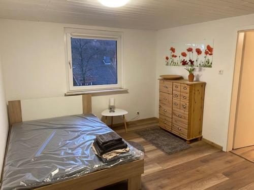 Un dormitorio con una cama y una cómoda y una ventana. en Niederfischbach Ferienwohnung, en Niederfischbach