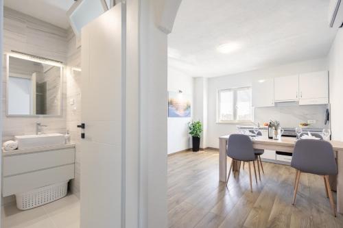 Una cocina con gabinetes blancos y una mesa y sillas. en Maloa One Bedroom 2, en Smokvica