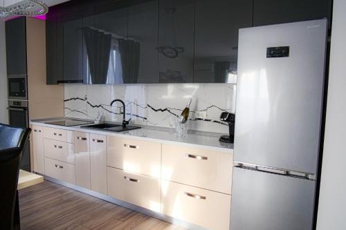 a kitchen with white cabinets and a white refrigerator at Apartament Panorama Baile Felix in Baile Felix