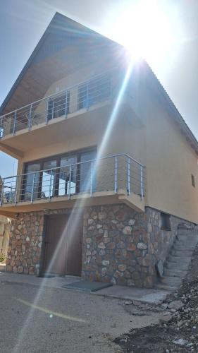 a house with a balcony and a stone wall at Apartments Orchidea in Žabljak