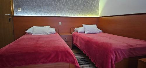 two beds in a room with red sheets and white pillows at SOBE/ROOMS RIVA in Zadar