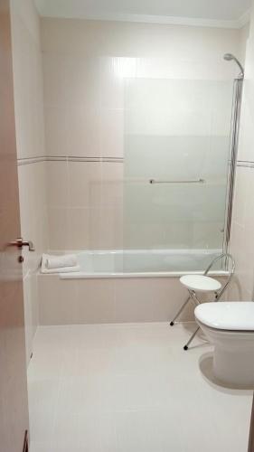 a white bathroom with a tub and a toilet at Apartamentos La Blanca in Nueva de Llanes