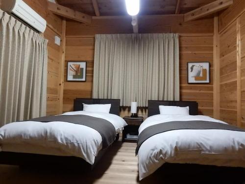 Dos camas en una habitación con paredes de madera. en Yadoya Sanbou, en Kioto