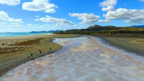 a group of people riding horses on the beach at S'Arrioleddu in Muravera