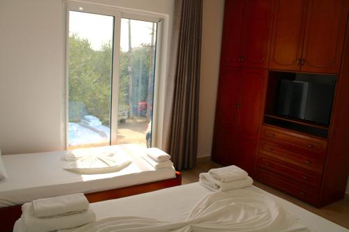 Un dormitorio con dos camas y un televisor y una ventana. en Vila Rafael Ksamil, en Ksamil
