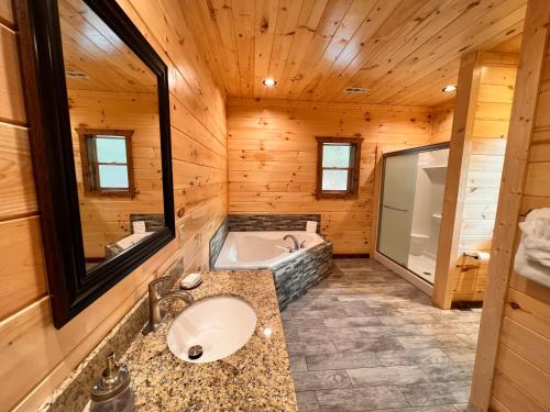a bathroom with a tub and a sink in a cabin at Blaze of Glory - New Luxury, 4BR, Theater, Arcade, EVC, Location in Sevierville