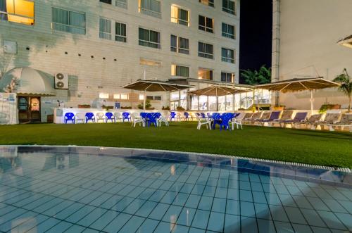 a pool with chairs and tables and a building at Royal Plaza Hotel in Tiberias