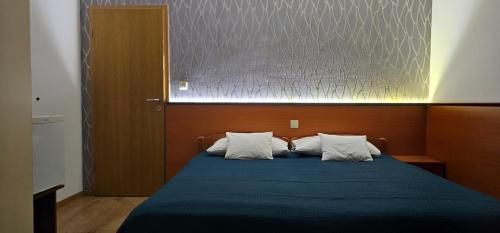 a bedroom with a blue bed with two pillows at SOBE/ROOMS RIVA in Zadar