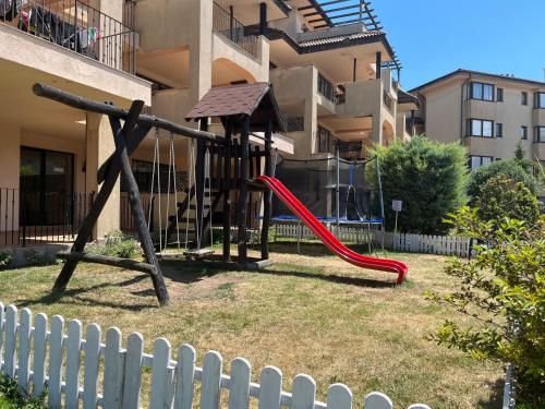 a playground with a red slide in front of a building at Kaliakria Vibes studio apartment in Topola